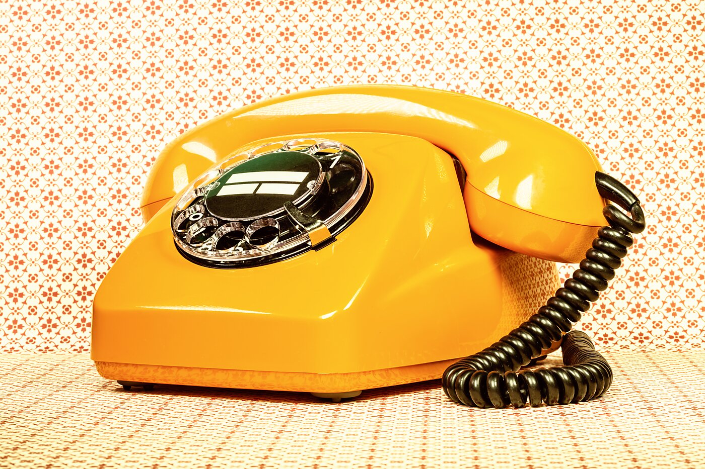 An old yellow rotary phone with a cord.